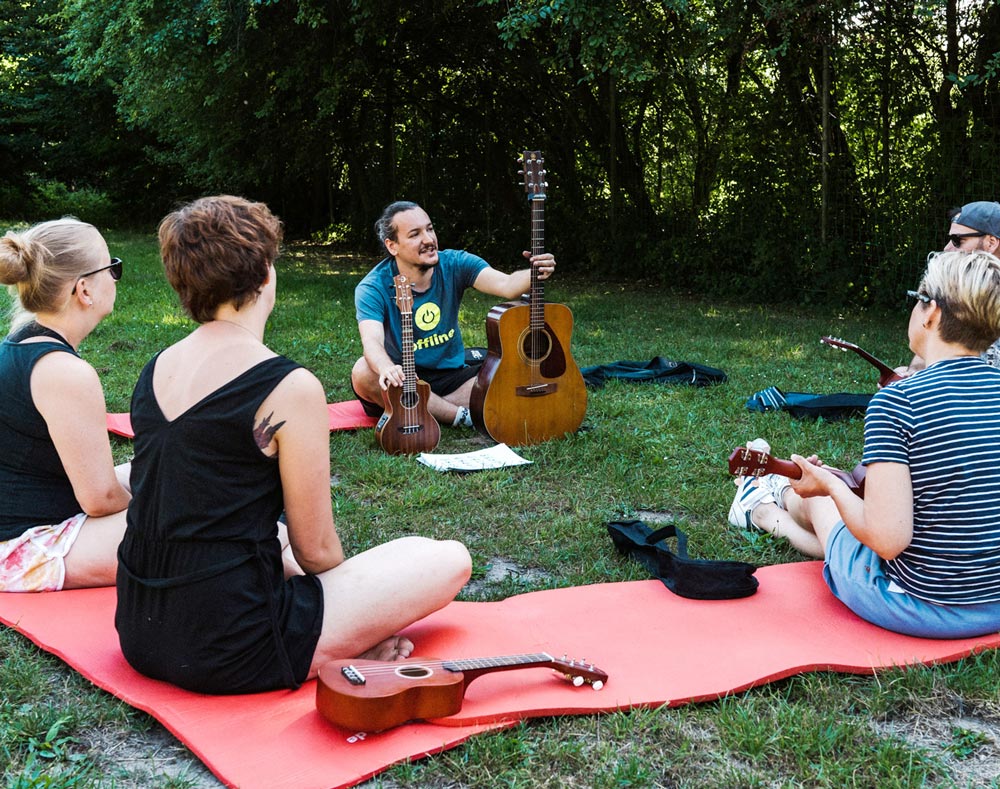 Teilnehmende eines Team-Offsites beim Ukulele-Workshop, spielend auf Ukulelen.