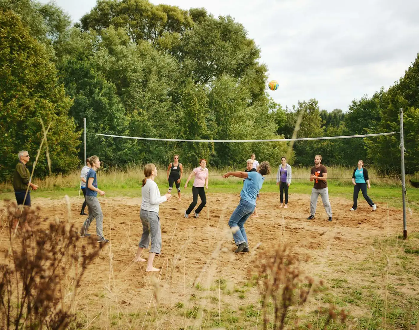 Gruppe von Kolleg:innen spielt Beach-Volleyball bei einem Team-Offsite.